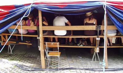 unter der hochgebundenen Rondellplane: Leute auf der Sitztribne von hinten